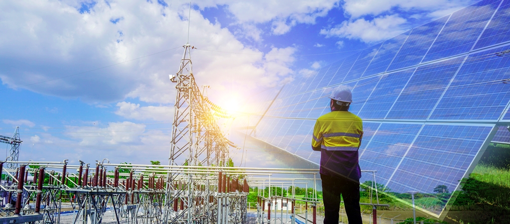 An engineer with helmet looking on to a solar project and transmission infrastructure