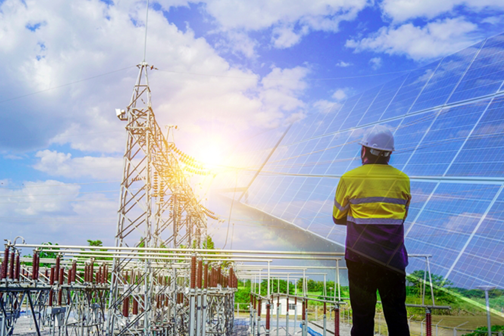An engineer with helmet looking on to a solar project and transmission infrastructure